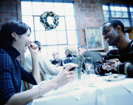A couple at a table in a restaurant laughing together.